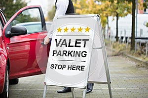 Young Male Valet Standing Near Valet Parking Sign