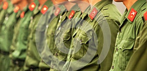 Young male vietnamese soldier in green uniform in a row, red star and cross swords icon in ribbons on shoulder. Vietnamese