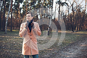 Young male walking in the forest in nature in a cream coat