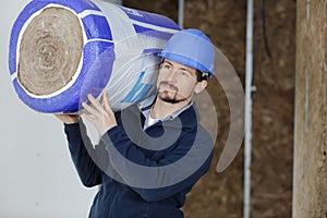 young male worker carrying roll insulation