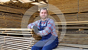 Young male worker in timber lumber warehouse. Concept - sale of lumber