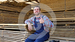 Young male worker in timber lumber warehouse. Concept - sale of lumber