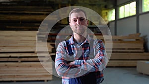 Young male worker in timber lumber warehouse. Wooden boards, lumber, industrial wood, timber. Pine wood timber