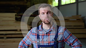 Young male worker in timber lumber warehouse. Wooden boards, lumber, industrial wood, timber. Pine wood timber