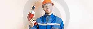 young male worker in uniform holding the electrical tool drill