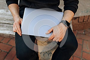 Young male working on his laptop computer in the city center. An independent person typing something in his document. chatting