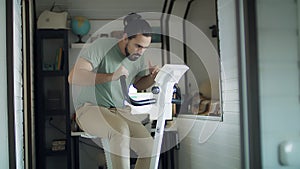 Young male working out on gym bike at the home