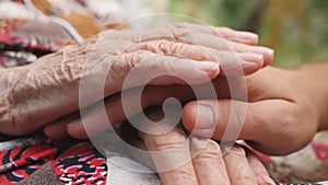 Young male and wrinkled hands comforting and stroking each other outdoor. Grandson and grandmother spending time