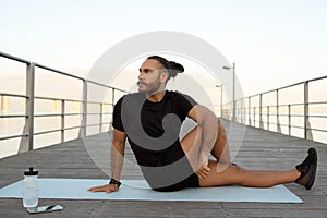 young man in activewear performing seated spinal twist asana outdoor