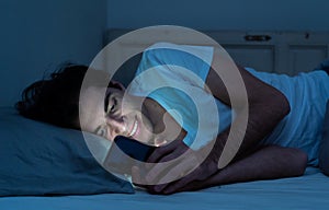 Young man addicted to online social media sleepless surfing on the Internet in bed