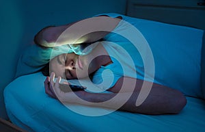 Young man addicted to online social media sleepless surfing on the Internet in bed