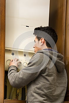 Young man adjusting the boiler or heater