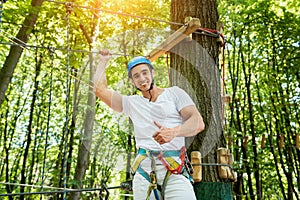 Young man in adventure rope park. Climbing Equipment.