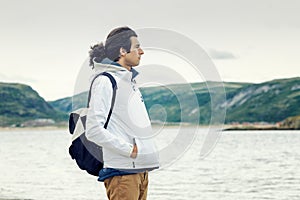 A young man against the backdrop of fierce mountains and the sea