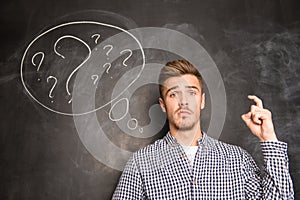 Young man against the background of chalkboard thinking about the problem