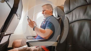 A young man in an airplane before a flight communicates on a mobile phone. photo