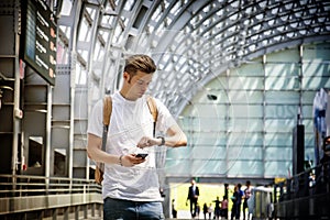 Young man at airport or station, looking at wrist watch