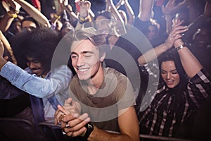 Young man amidst crowd enjoying at nightclub