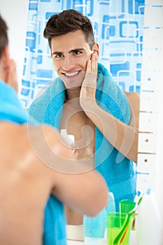 Young man applying aftershave photo