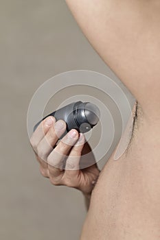 Young man applying deodorant to his armpits photo