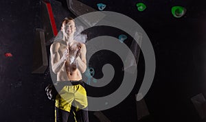 Young man applying magnesium powder before climbing in bouldering gym