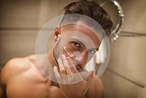 Young man applying moisturizing cream on face