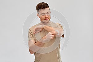 Young man applying pain medication to his elbow