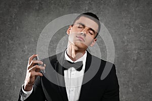 young man applying perfume on grey stone background