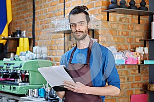 Young man in apron, food service worker, small business owner entrepreneur with work papers