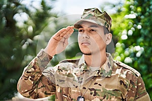 Young man army soldier saluting at park