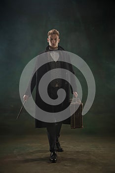 Young man in art action isolated on dark green background. Retro style, comparison of eras concept.