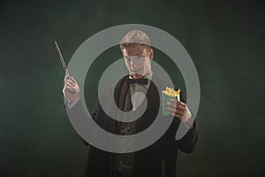 Young man in art action isolated on dark green background. Retro style, comparison of eras concept.