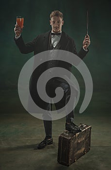 Young man in art action isolated on dark green background. Retro style, comparison of eras concept.