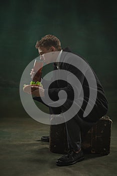 Young man in art action isolated on dark green background. Retro style, comparison of eras concept.