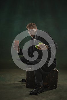 Young man in art action isolated on dark green background. Retro style, comparison of eras concept.