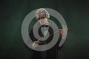 Young man in art action isolated on dark green background. Retro style, comparison of eras concept.