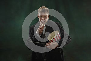 Young man in art action isolated on dark green background. Retro style, comparison of eras concept.