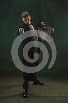 Young man in art action isolated on dark green background. Retro style, comparison of eras concept.