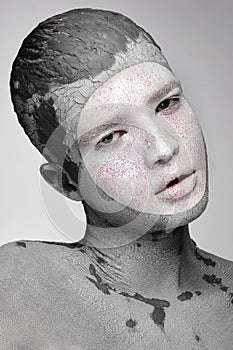 Young man with art creative make-up with mud on his face. Cosmetic mask.