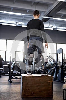 young man with artificial legs at gym