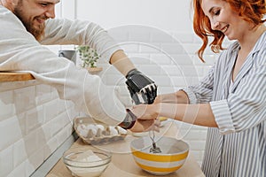 A young man with artificial limb are cooking in the kitchen with his girlfriend