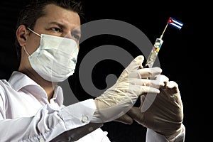 Young man as a doctor gives a medical injection to Cuban flag on a black background