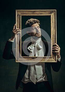 Young man as Dorian Gray on dark background. Retro style, comparison of eras concept.