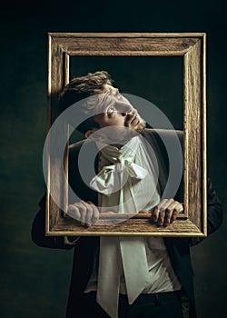 Young man as Dorian Gray on dark background. Retro style, comparison of eras concept.