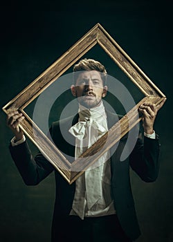 Young man as Dorian Gray on dark background. Retro style, comparison of eras concept.