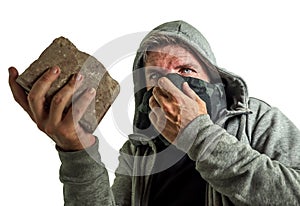 Young man as fanatic and aggressive anarchist rioter . furious and scary violent anti-system protester in face mask throwing brick