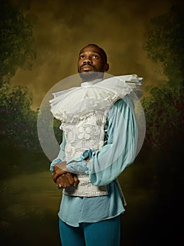 Young man as a medieval knight on dark background