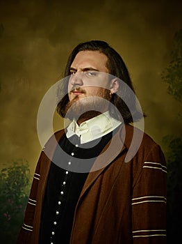 Young man as a medieval knight on dark background