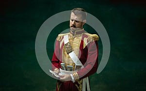 Young man as Nicholas II on dark green background. Retro style, comparison of eras concept.