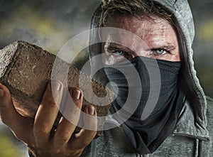 Young man as ultra and radical anarchist rioter . furious antifa protester in face mask throwing brick hostile on street on